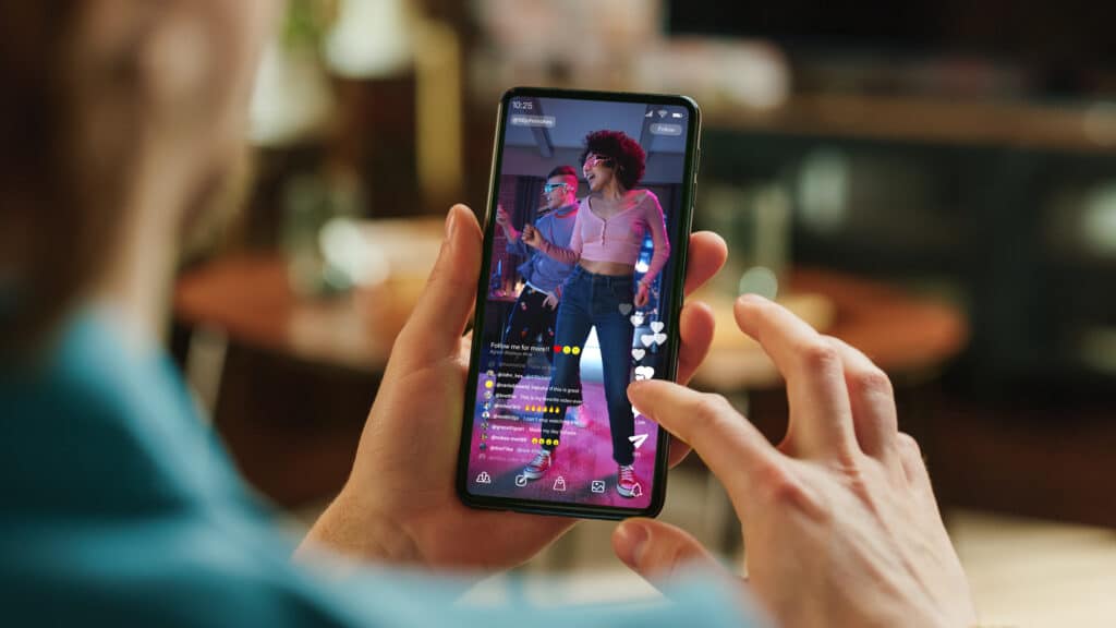 person watching two social media influencers dancing on a livestream from their phone