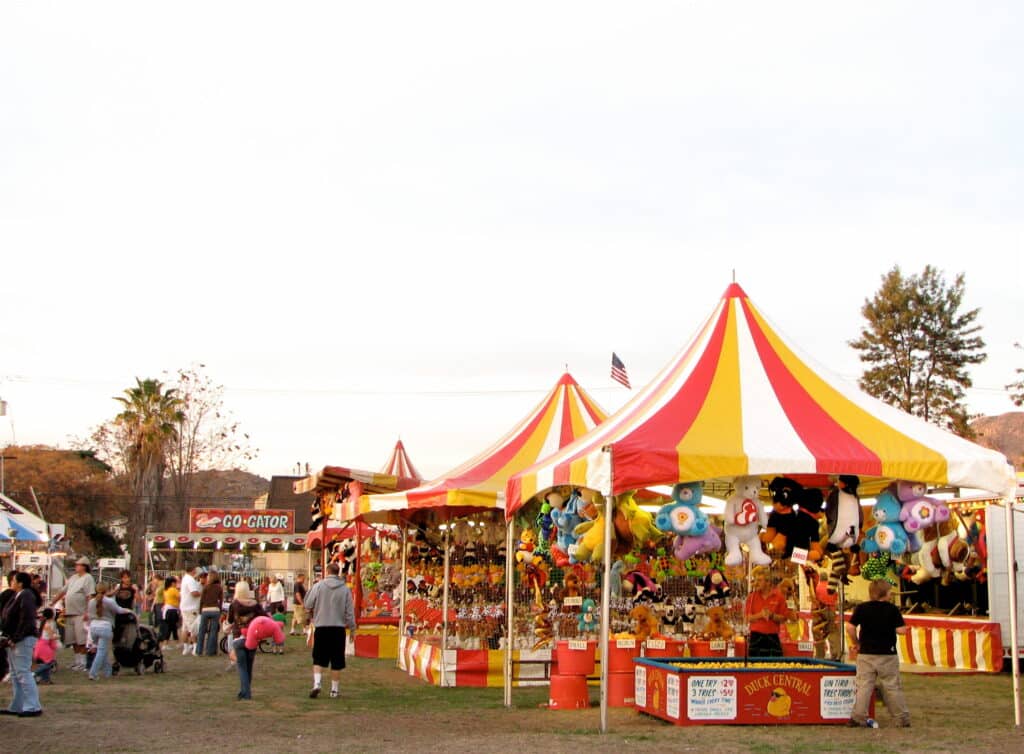 row of yellow, red, and white carnival tents with toy prizes and games underneath