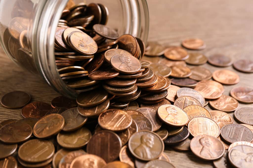 glass jar of pennies poured on a table