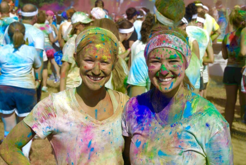 Two women covered in paint after a color run school fundraiser