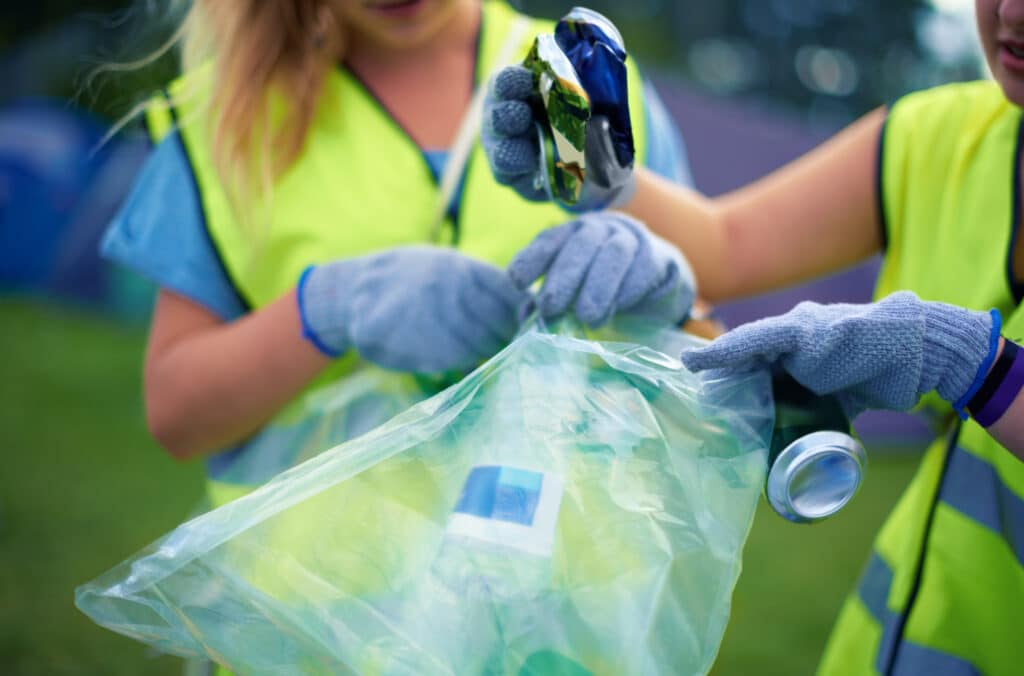 Cropped shot of two young women picking up trash after a festival.