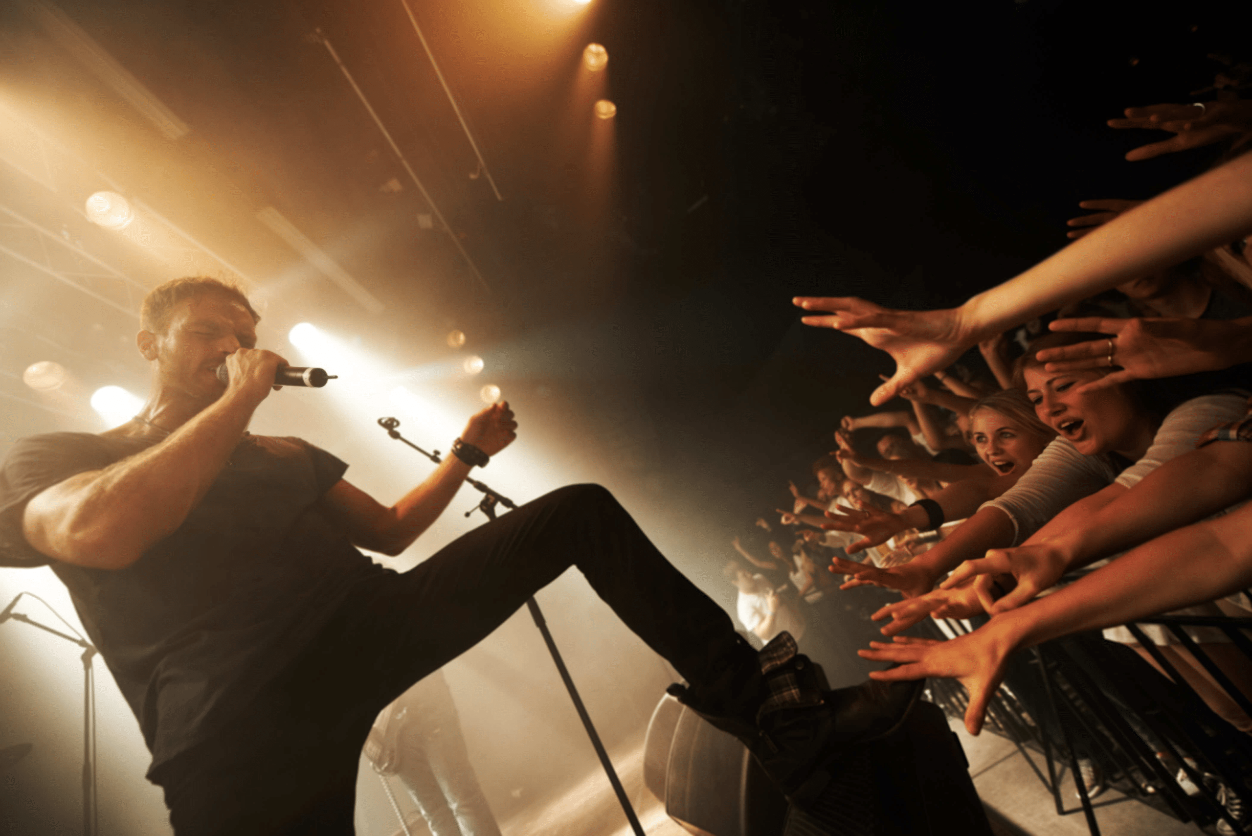 male performing stepping speaker and singing to a crowd of fans